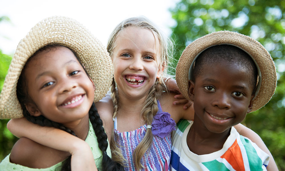 Three young kids smiling at camera